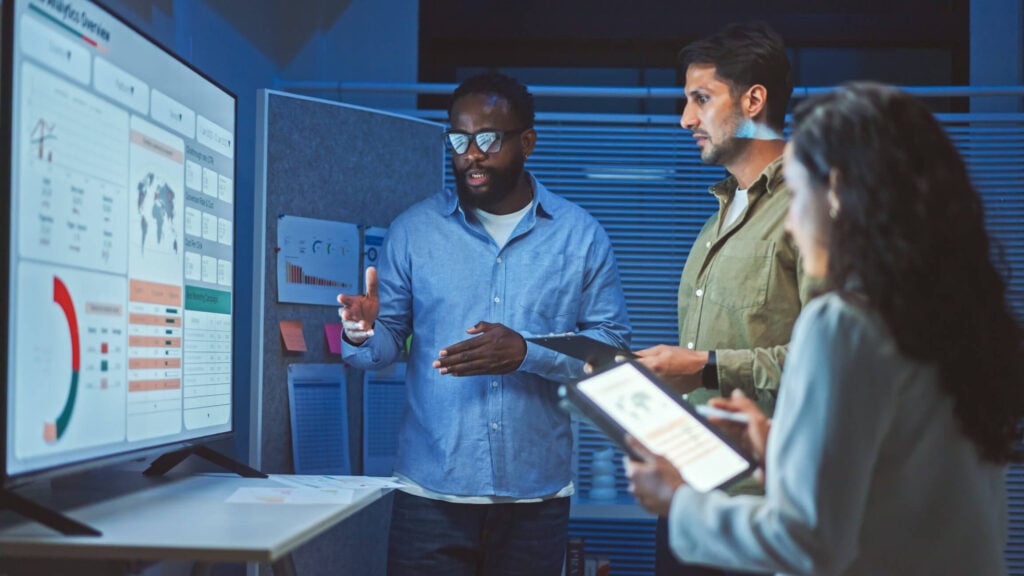Accounting team reviewing data on multiple screens in modern office